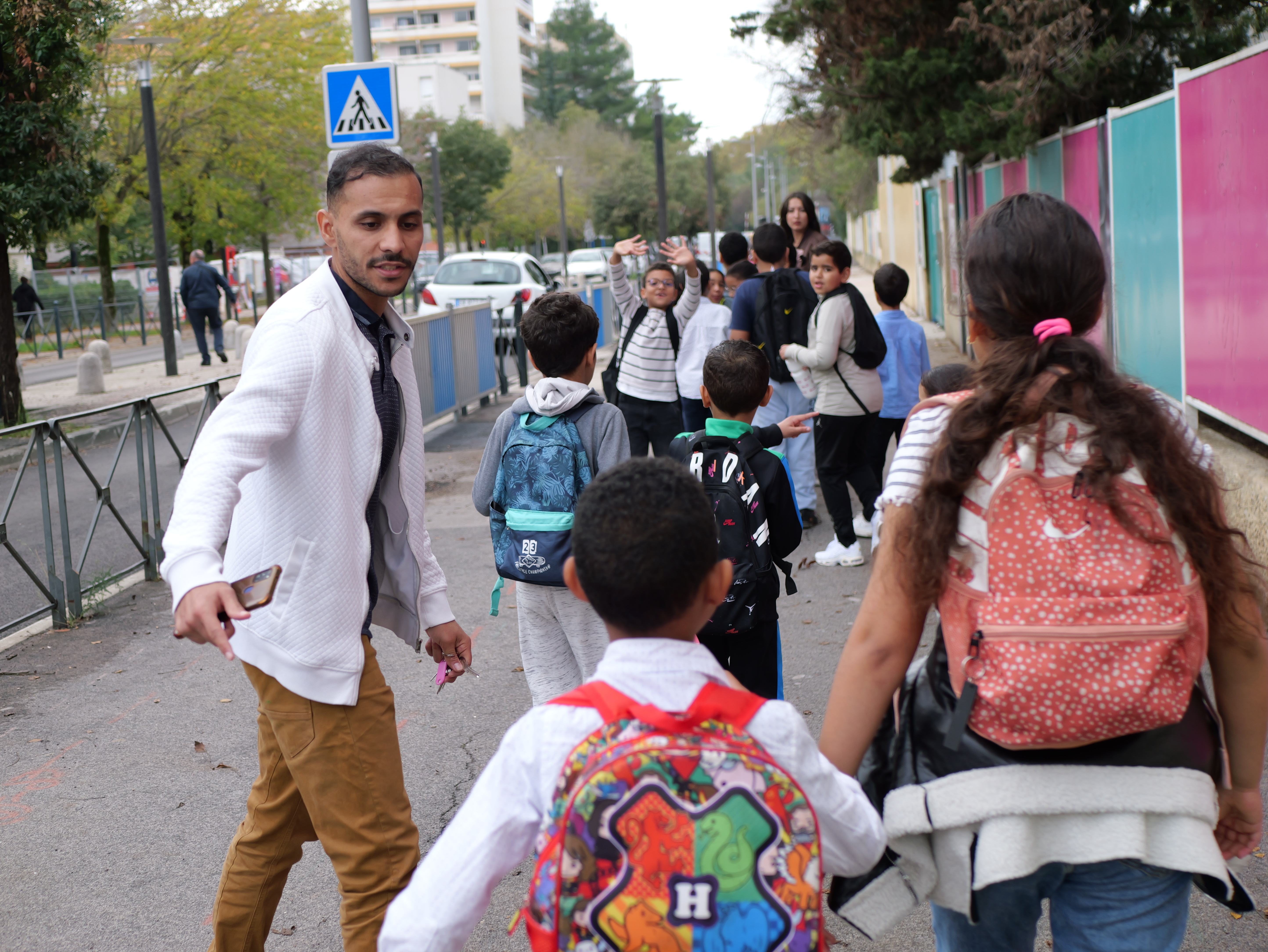 Un animateur accompagne le groupe d'enfants à la sortie de l'école